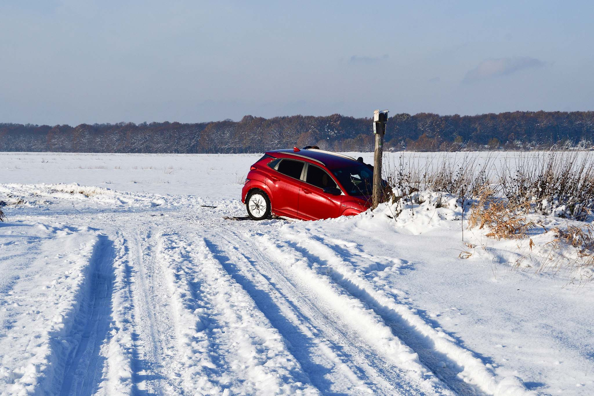 Samochód, który utknął w rowie po tym jak wpadł w poślizg i zjechał z ośnieżonej drogi