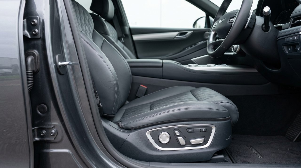 Biały sedan Genesis G80 zaparkowany na otwartej przestrzeni z dala od zabudowań.